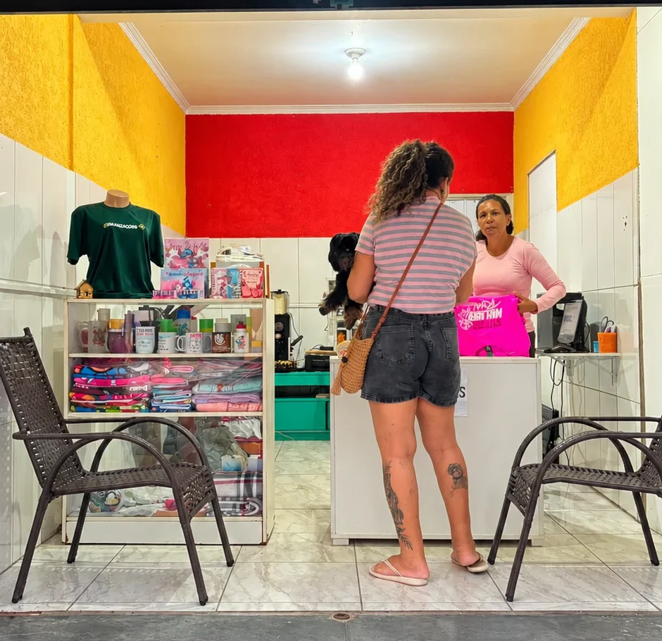 Loja da Mimo Criativo Personalizados: prateleiras com canecas, chinelos e camisetas personalizadas, e uma cliente sendo atendida no balcão